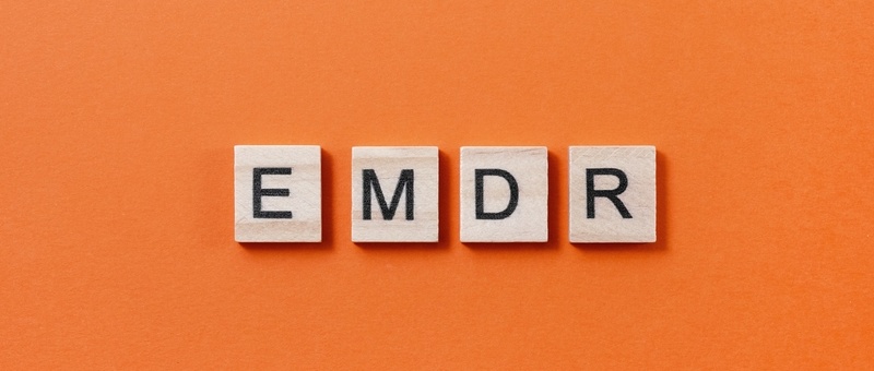 EMDR letters printed on separate wooden blocks against an orange background.